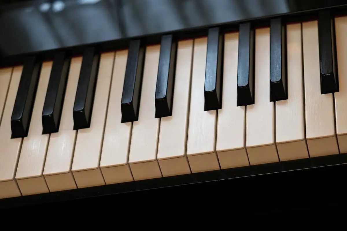 Clapele alb-negru ale unui pian, văzute de aproape, pe un instrument muzical cu claviatură