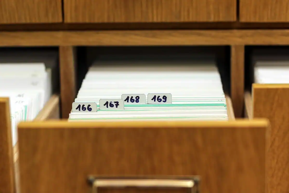Fișier cu cartele numerotate într-un sertar de lemn, unde se păstrează evidența datelor