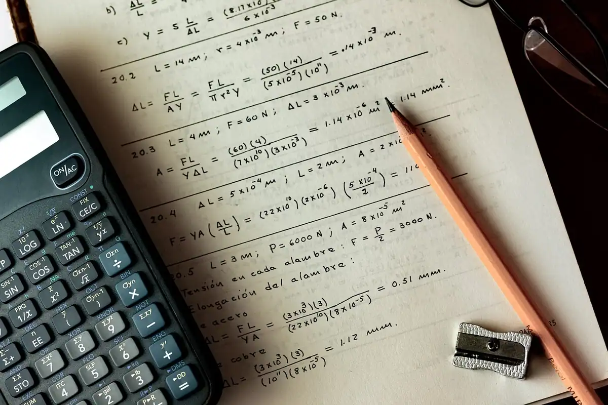 Calculator și caiet cu formule scrise de mână, folosite pentru a calcula economia din refinanțare