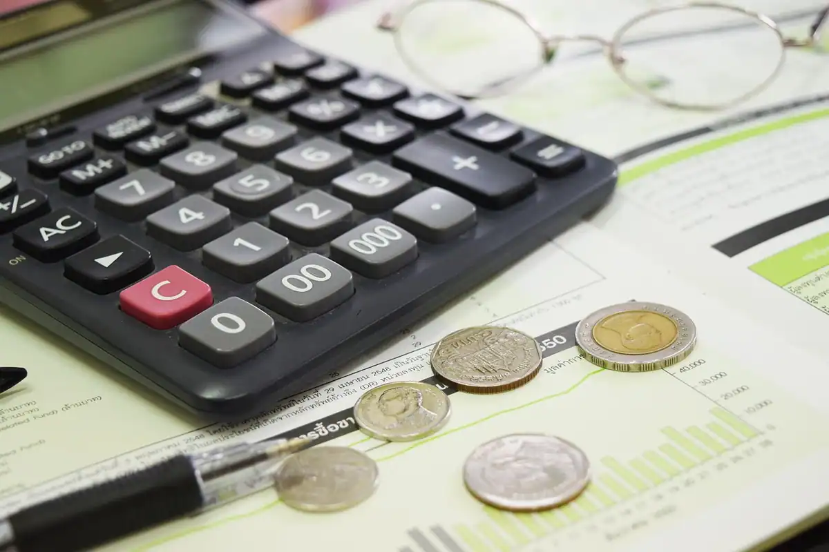 Calculator, monede și hârtii de calcul pe birou, pentru a estima compensația la rambursare anticipată