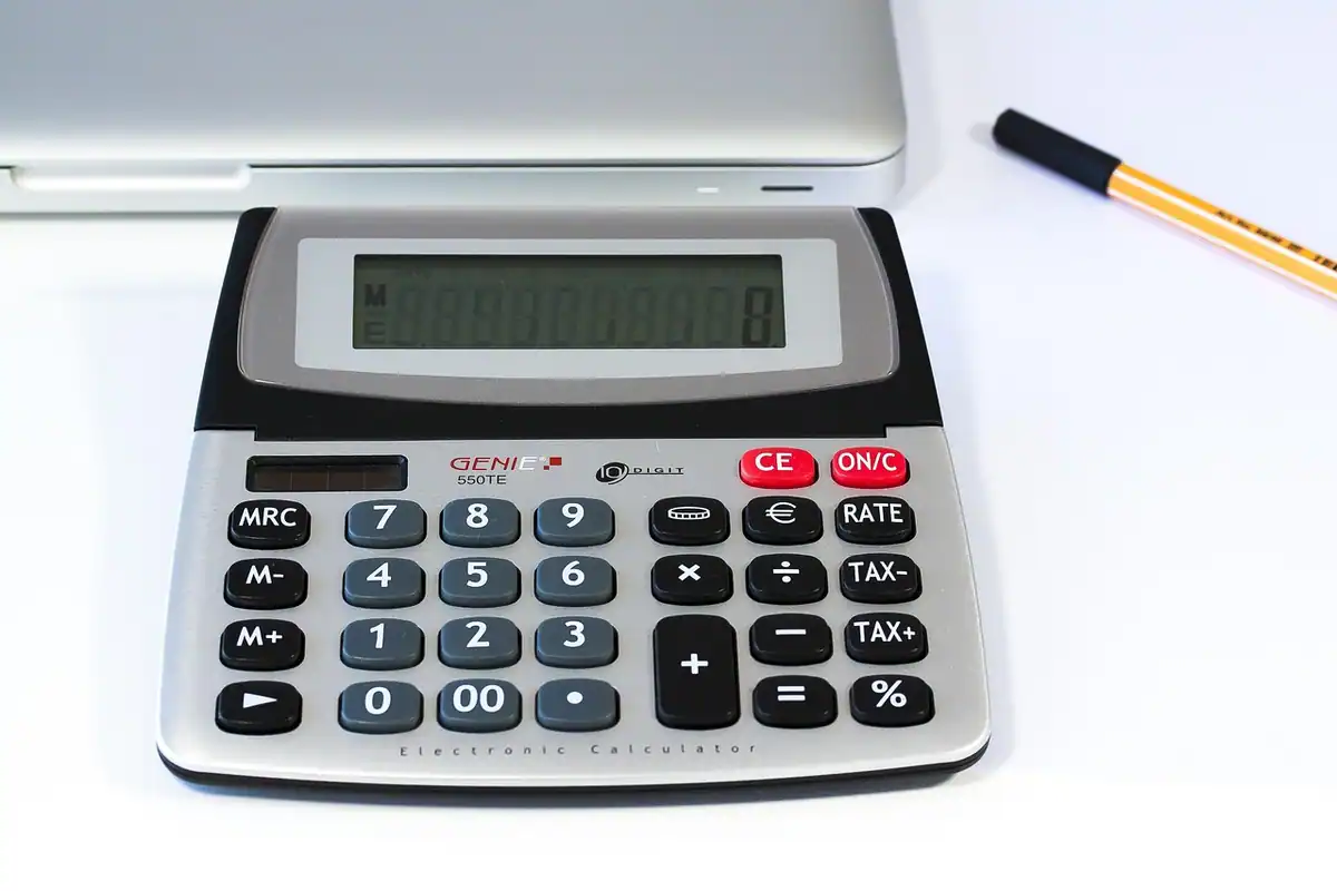 Calculator de birou și un pix pe masă albă, pentru a aduna ratele mai multor credite