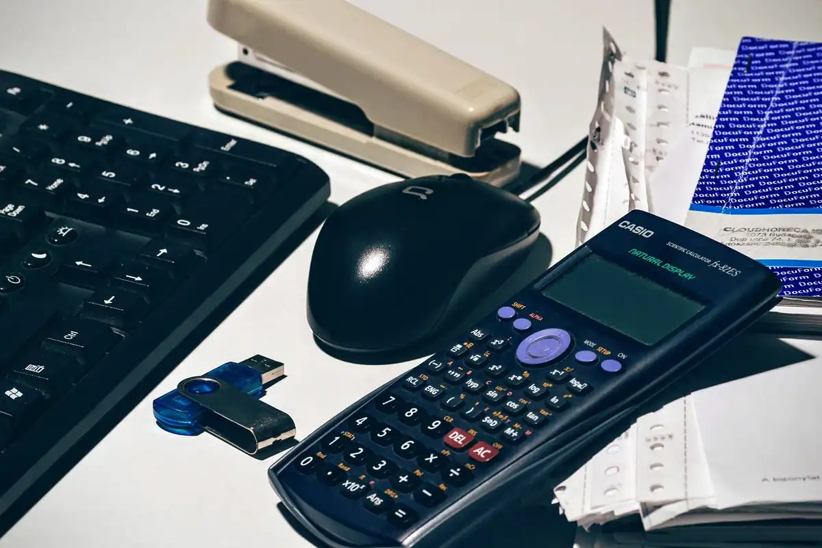 Tastatură, mouse și calculator pe un birou, pentru socotirea costurilor refinanțării ipotecare