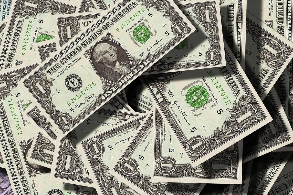 Mai multe bancnote de dolari americani, strânse laolaltă, simbol al valutei și al economiilor