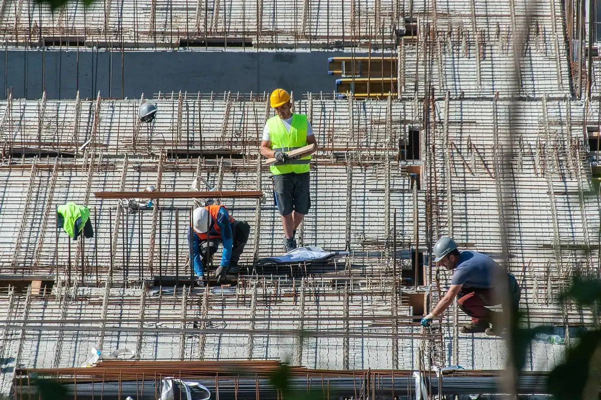 Muncitori pe schele la un șantier de construcție, unde se ridică o casă nouă