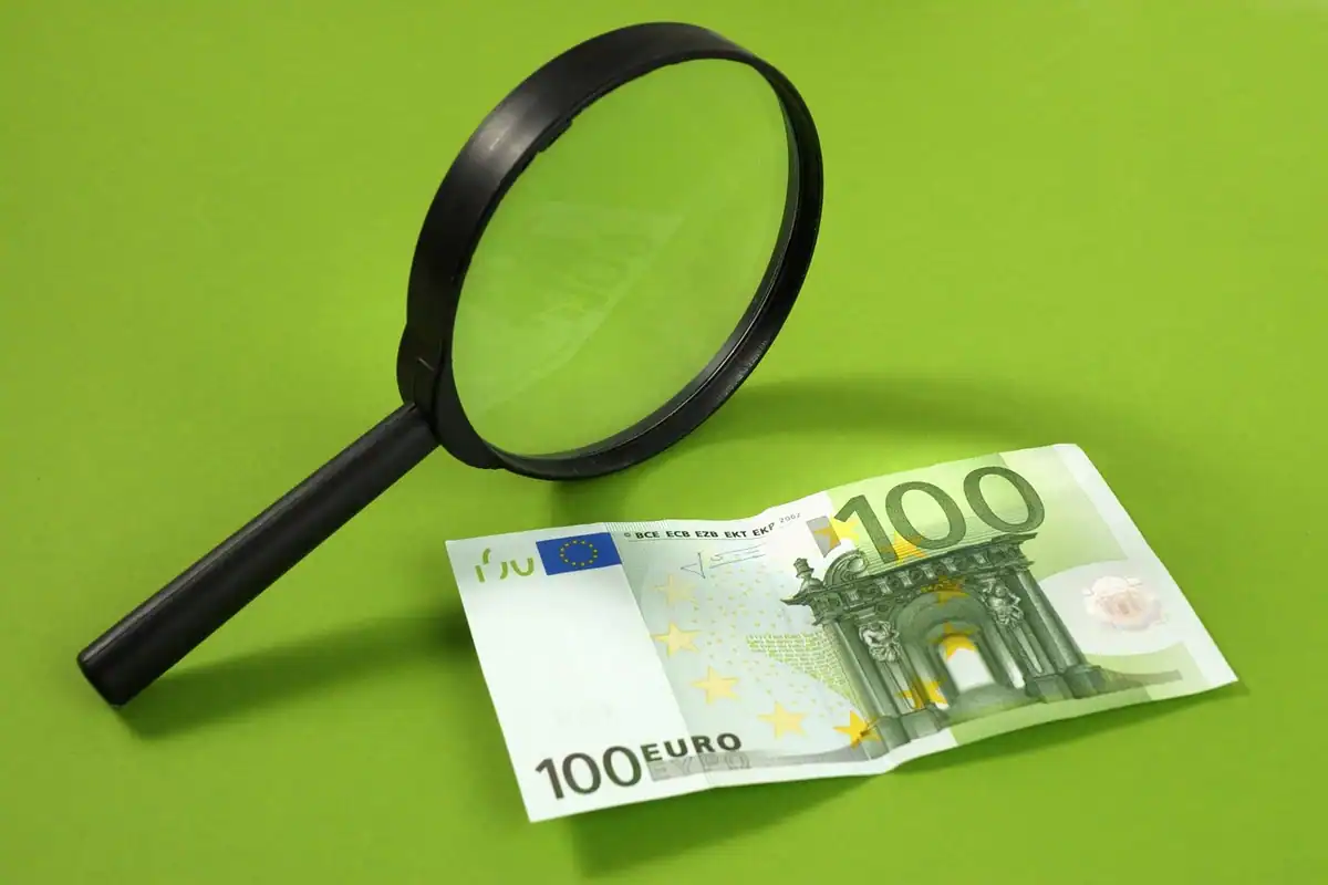 O lupă mare așezată pe un fundal de hârtie, simbol al cercetării atente a detaliilor