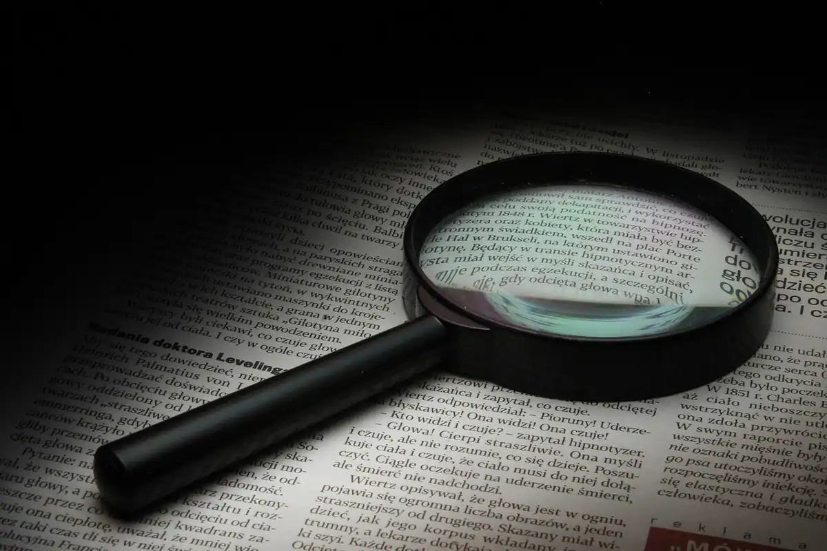 O lupă așezată pe un ziar, care mărește textul tipărit al paginii