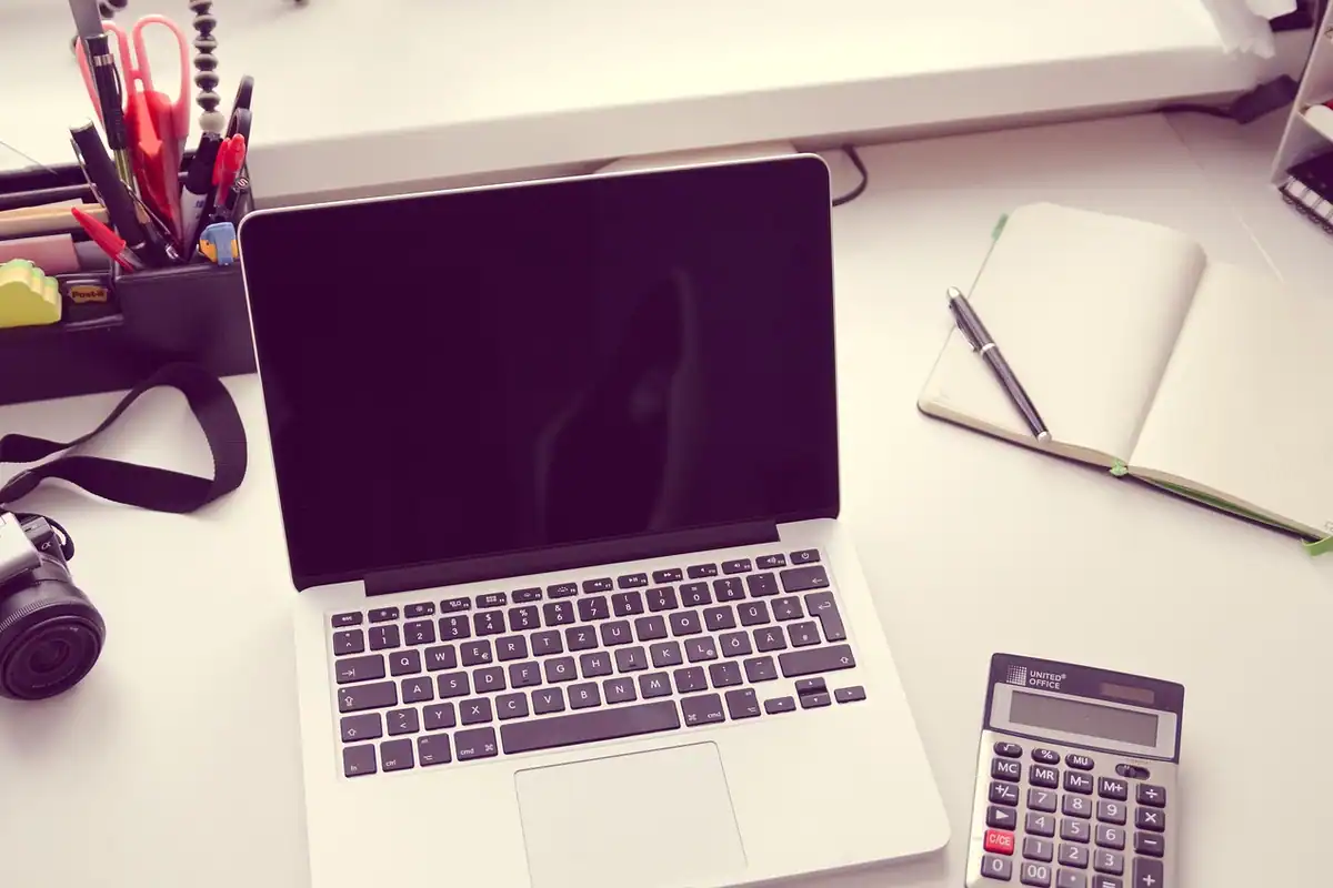 Un calculator lângă un ziar și o tastatură de laptop, pentru calculul cheltuielilor lunare