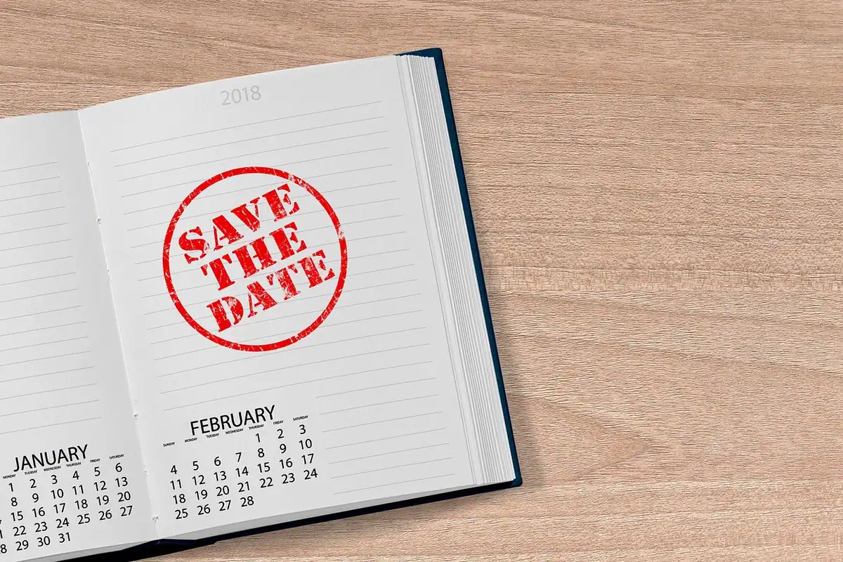 O agendă deschisă cu calendar pe o masă de birou, cu luni, zile și loc pentru notițe