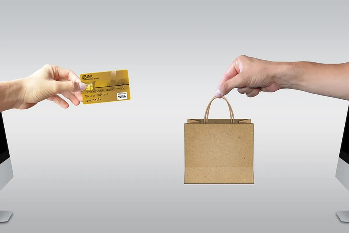 Mână care întinde un card auriu spre o pungă de hârtie ținută de altă mână
