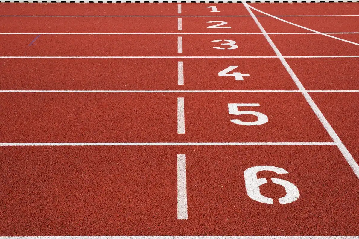 Pistă de alergare cu linii și numere la linia de start, pe un stadion sportiv