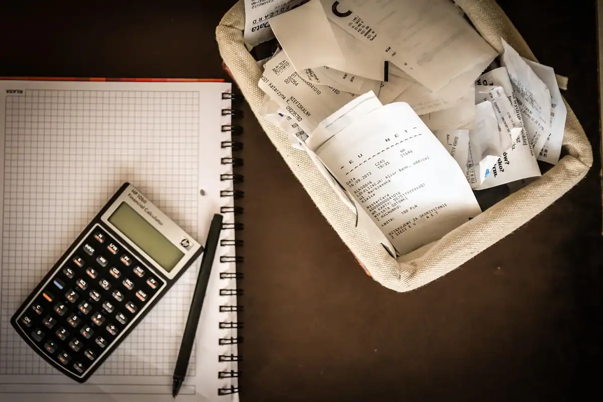 Calculator, carnet și un coș cu bonuri pe masă, pentru bugetul lunar