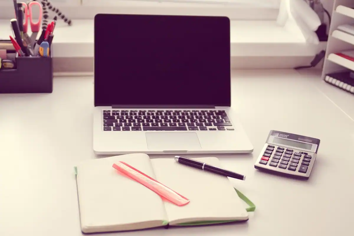 Laptop, carnet și calculator mic pe un birou, pentru calculul veniturilor din cerere