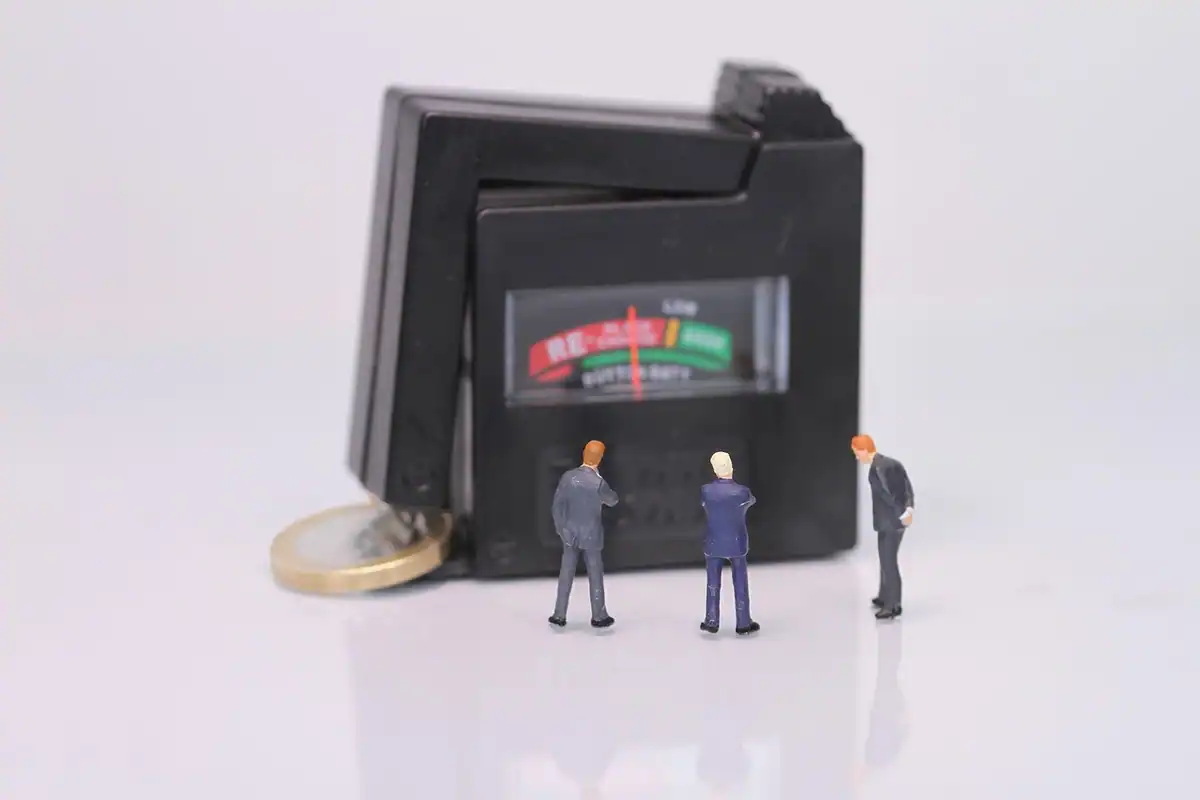 Figurine în miniatură lângă un aparat de măsură și o monedă, pentru evaluarea la preaprobare