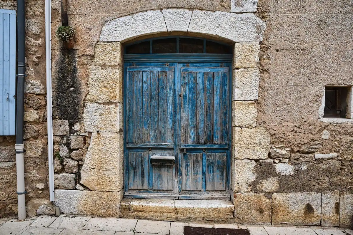 O ușă albastră într-o fațadă de piatră, pe o stradă liniștită, în stil rustic