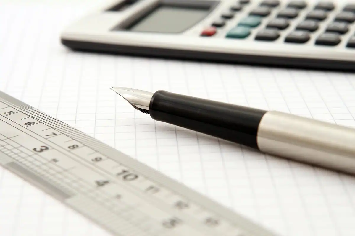 Calculator, riglă și stilou pe hârtie milimetrică, pentru a alege între rată și perioadă