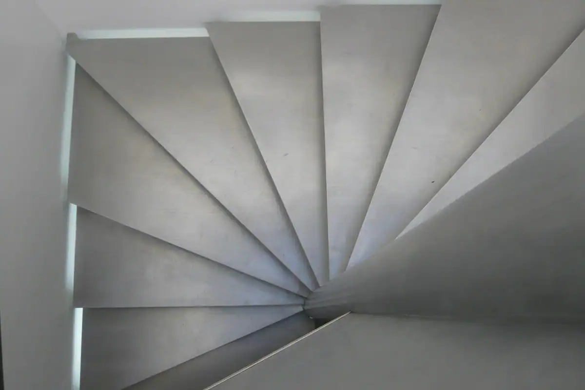 Scară în spirală văzută de sus, cu trepte gri care coboară, ca ratele descrescătoare
