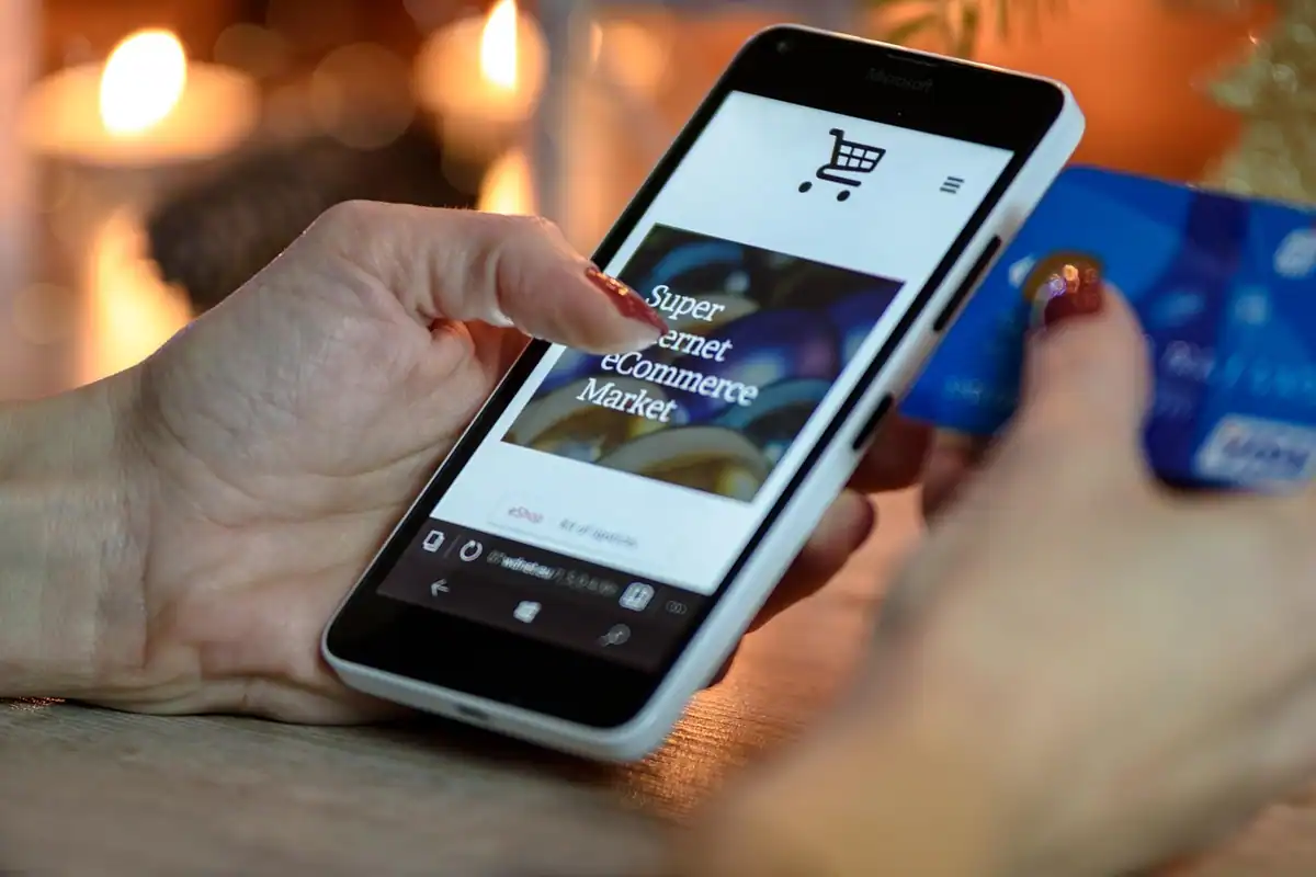 Mână care folosește un telefon cu magazin online, în timp ce ține un card