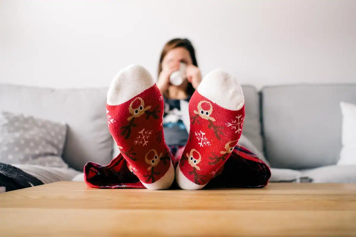 O persoană relaxată pe canapea în sufragerie, cu picioarele în șosete, într-un decor cald de acasă