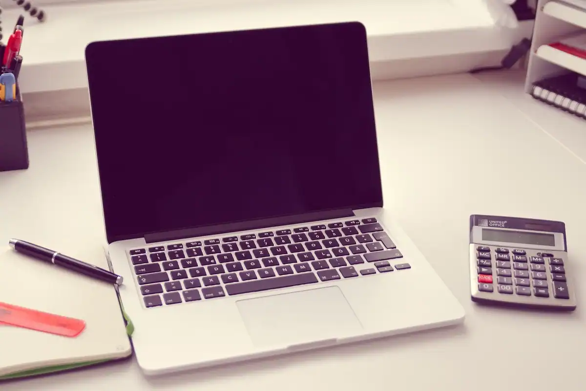 Un calculator lângă un ziar și o tastatură de laptop, pentru calculul veniturilor